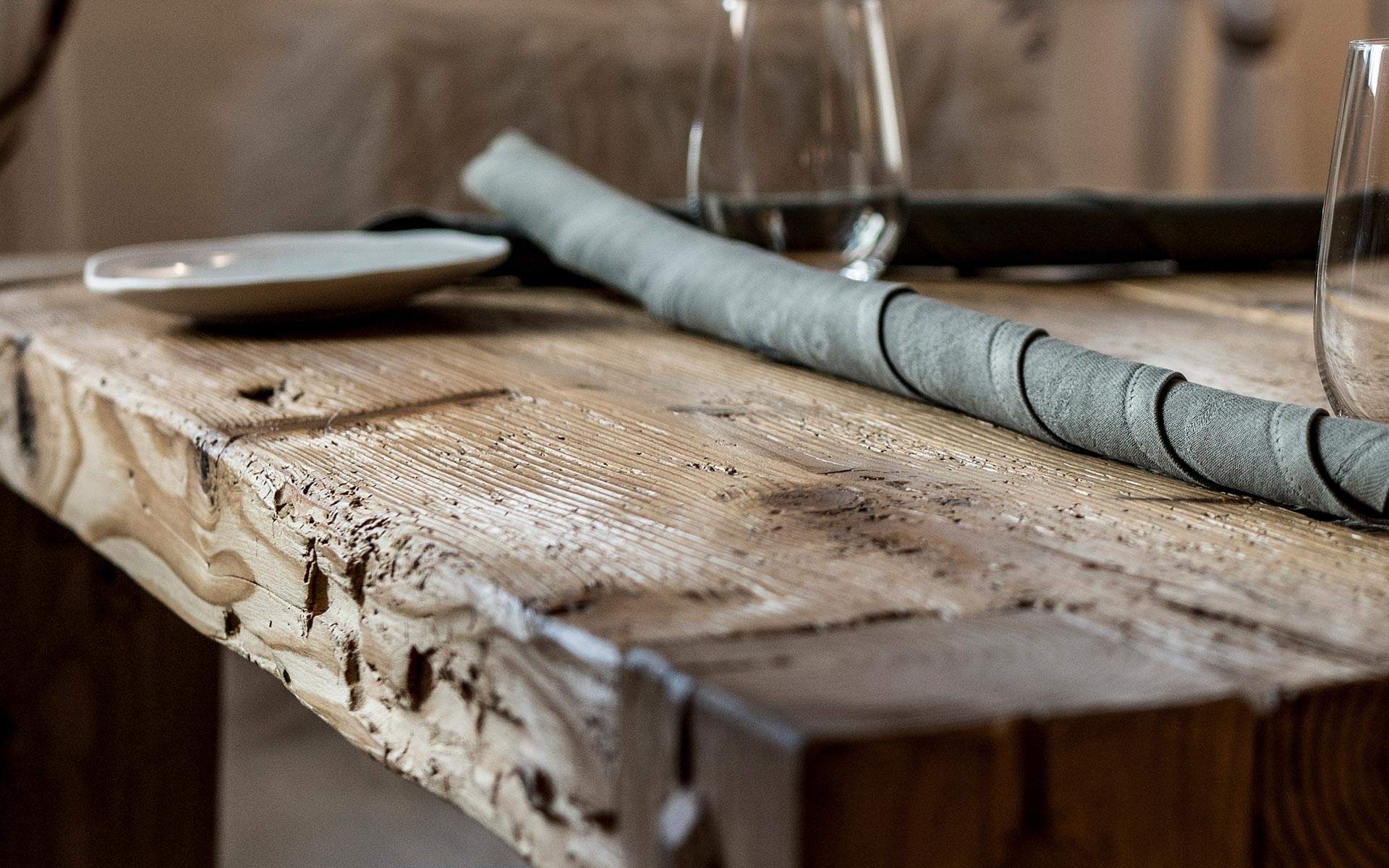 Detail of the table in raw pine wood prepared with glasses and plates